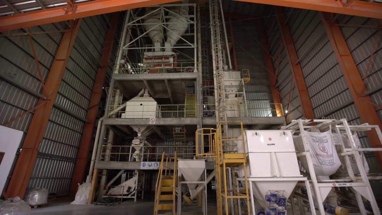 Interior de una planta de alimento balanceado para aves de engorde: torre de proceso, tolvas de dosificación y big bags de materia prima