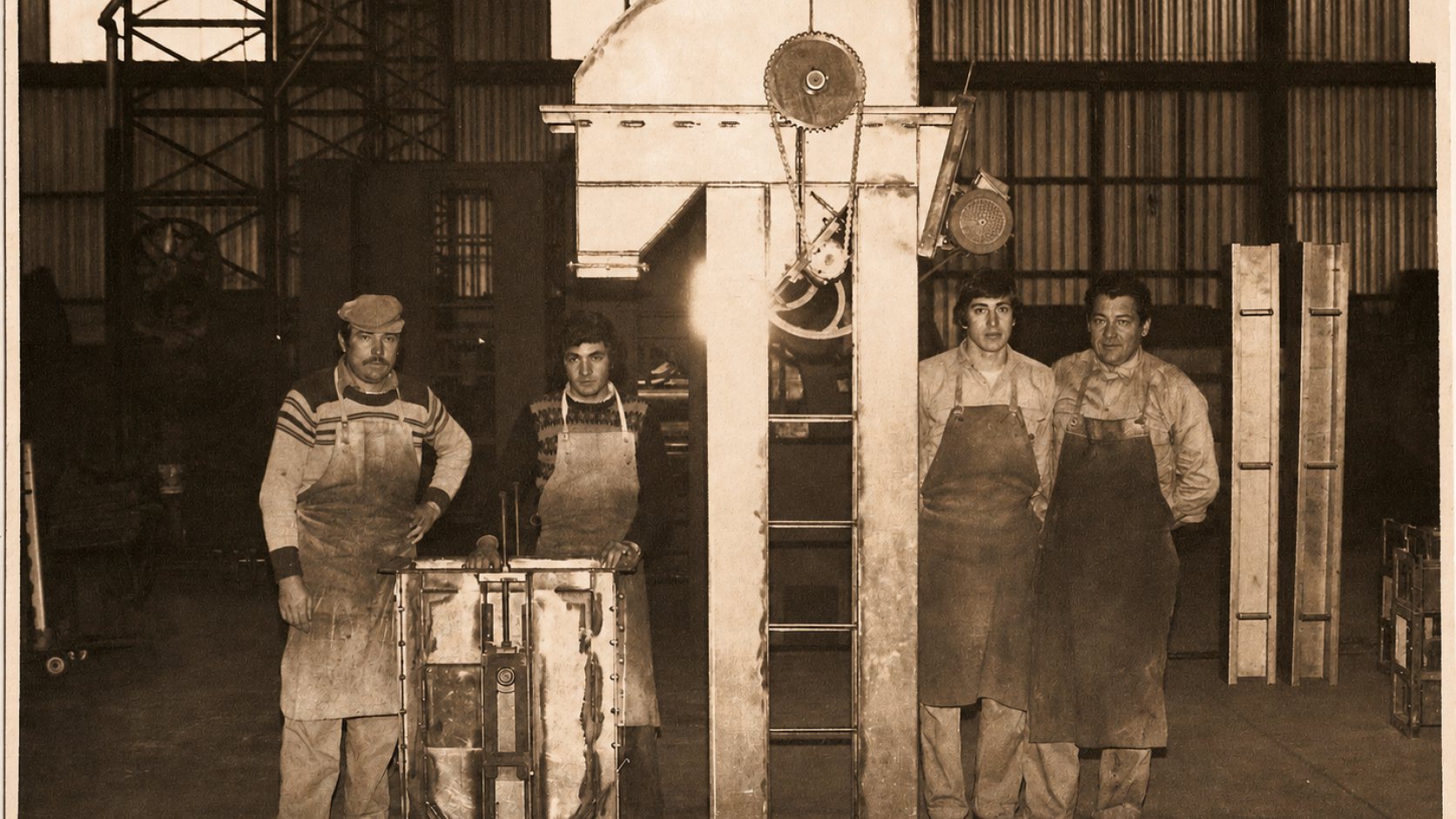 Cuatro operarios junto a una estructura metálica en armado dentro del taller