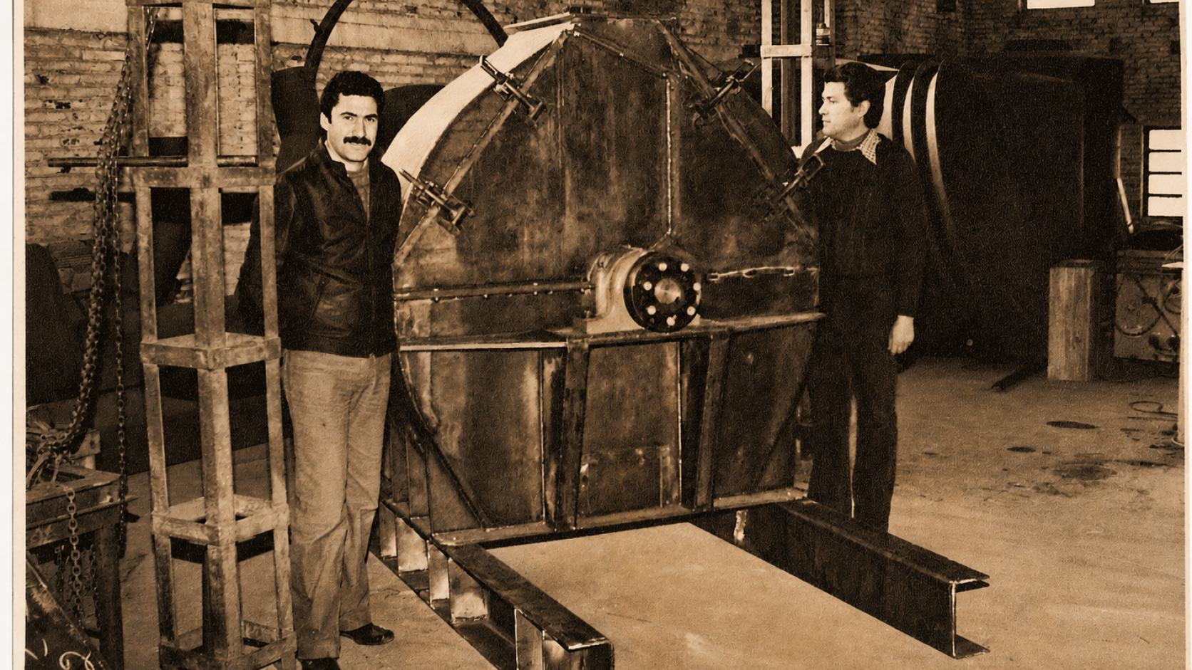 Dos operarios junto a una mezcladora de gran porte terminada en el taller