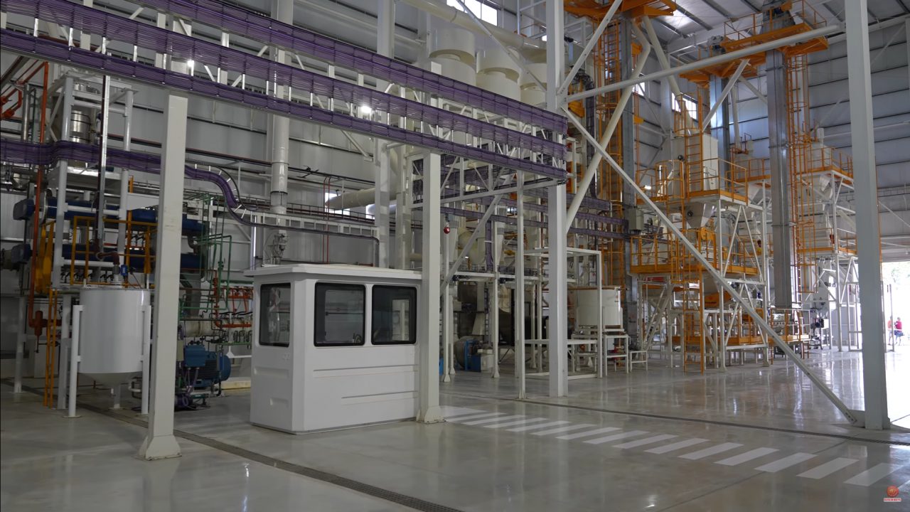 Interior de uma fábrica de pet food, com transportadores aéreos e cabine de controle de linha